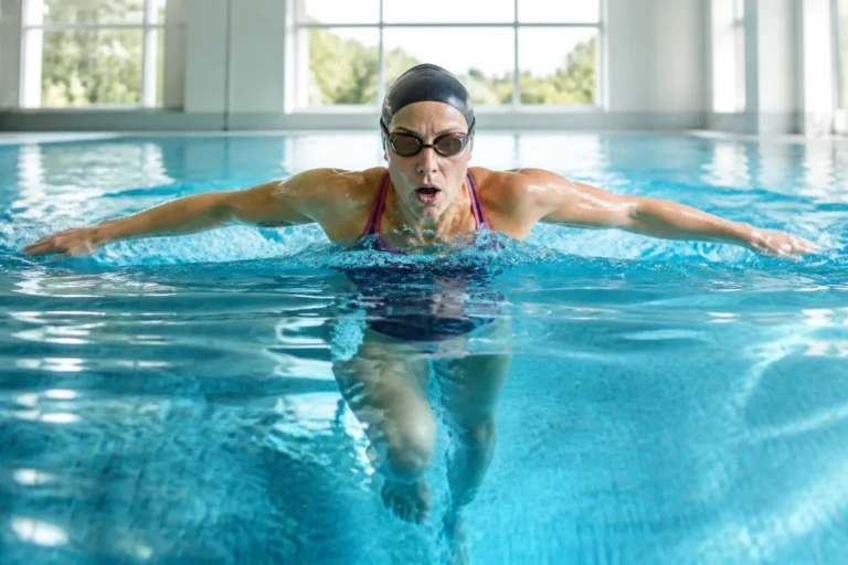 Nageuse adulte en piscine, illustrant la natation pour maigrir et le renforcement des bras, abdominaux, dos et jambes