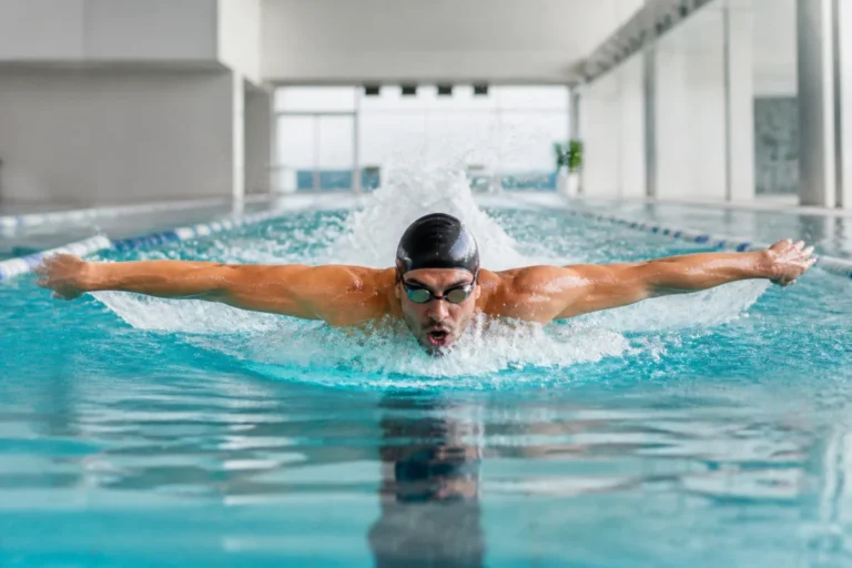 Nageur adulte en papillon dans une piscine intérieure, illustrant combien de temps nager pour perdre du poids efficacement